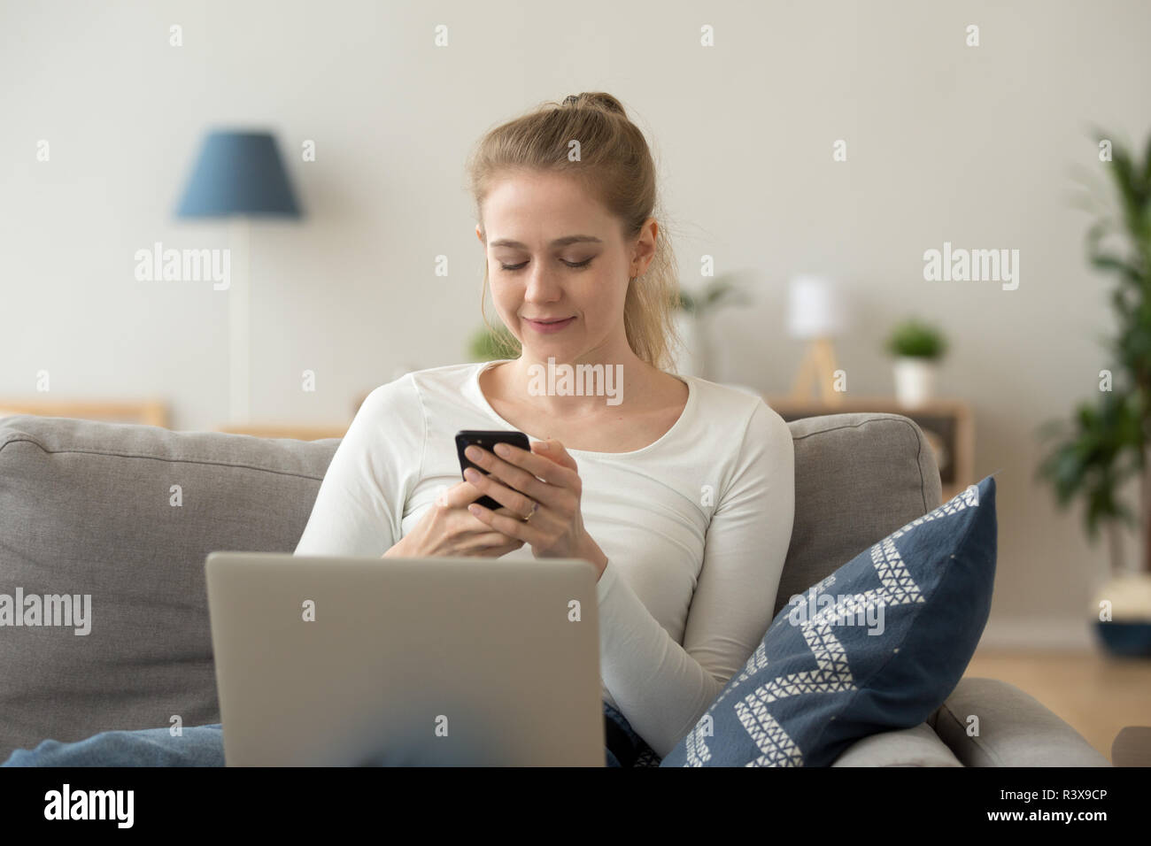 Smiling girl texting using smartphone à la maison Banque D'Images