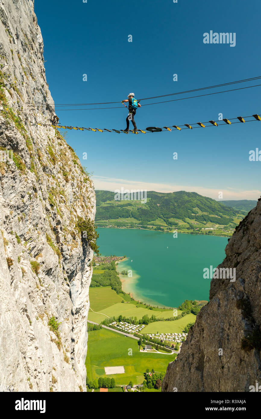 Climber marcher sur un pont élevé sur Drachenwand via ferrata, au-dessus du lac de Mondsee, Autriche Banque D'Images