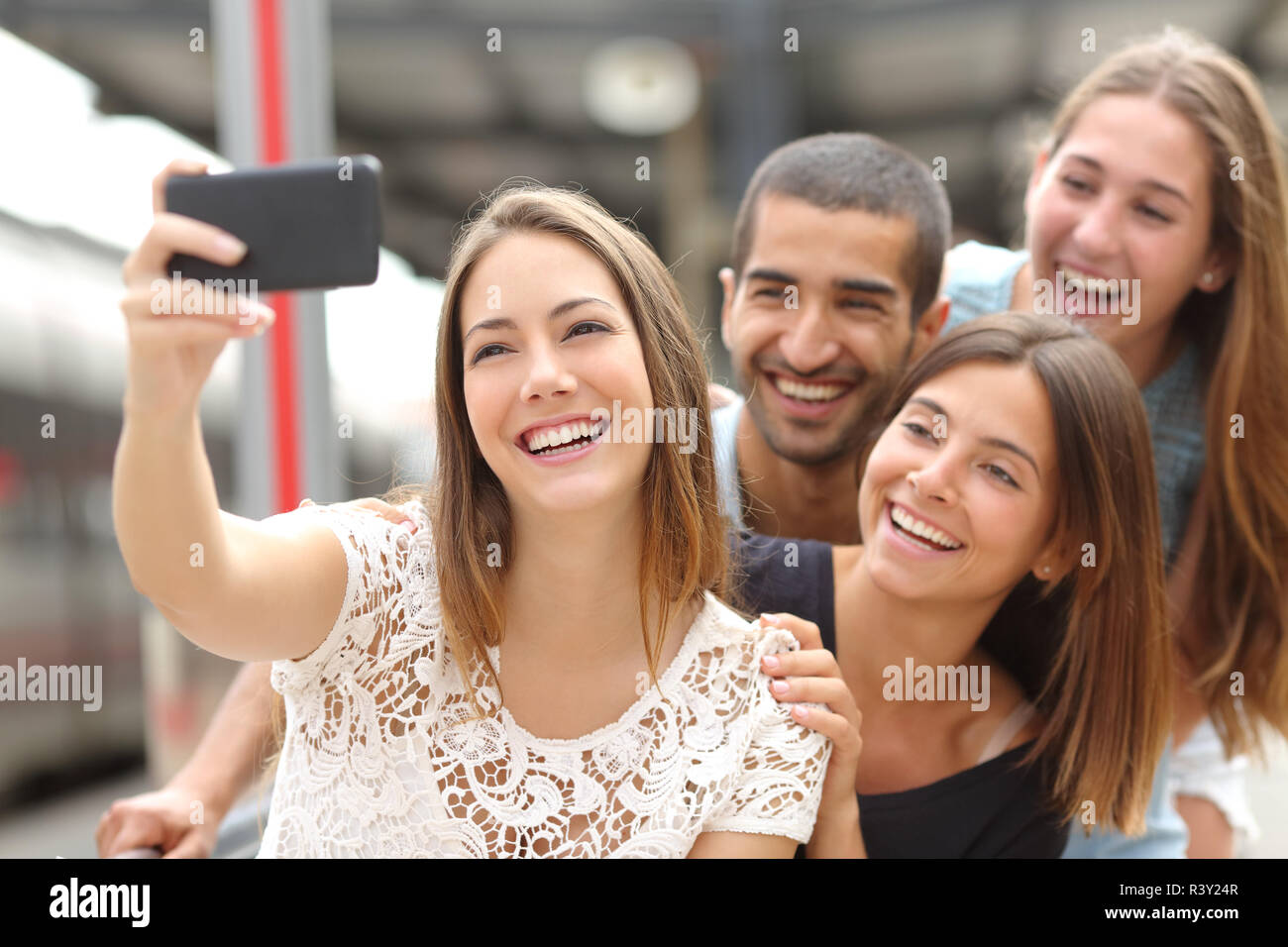 Groupe de quatre amis en tenant un téléphone intelligent avec selfies Banque D'Images