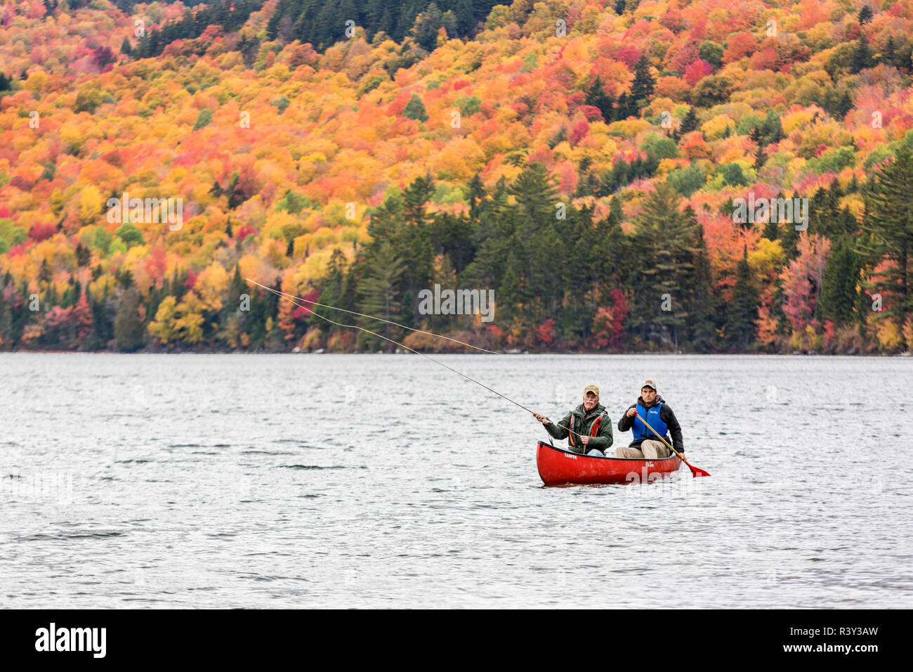 Deux hommes la pêche à la mouche à partir d'un canoë sur Greenough étang dans l'emplacement de Wentworth, New Hampshire. De l'automne. La Forêt du Nord. (MR) Banque D'Images
