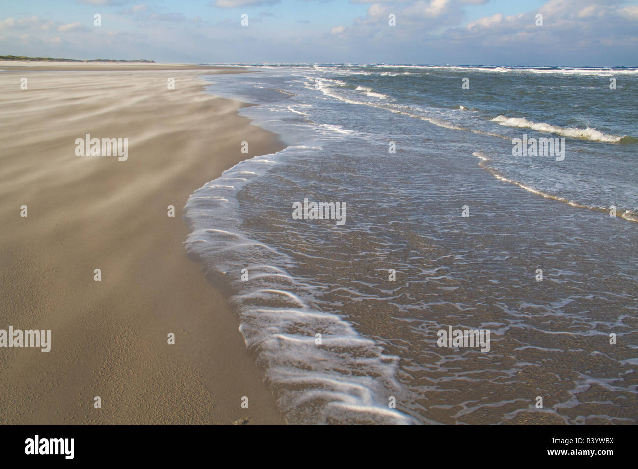 Sur la plage un jour de tempête : sable souffle sur la plage et de la mousse sur l'eau Banque D'Images