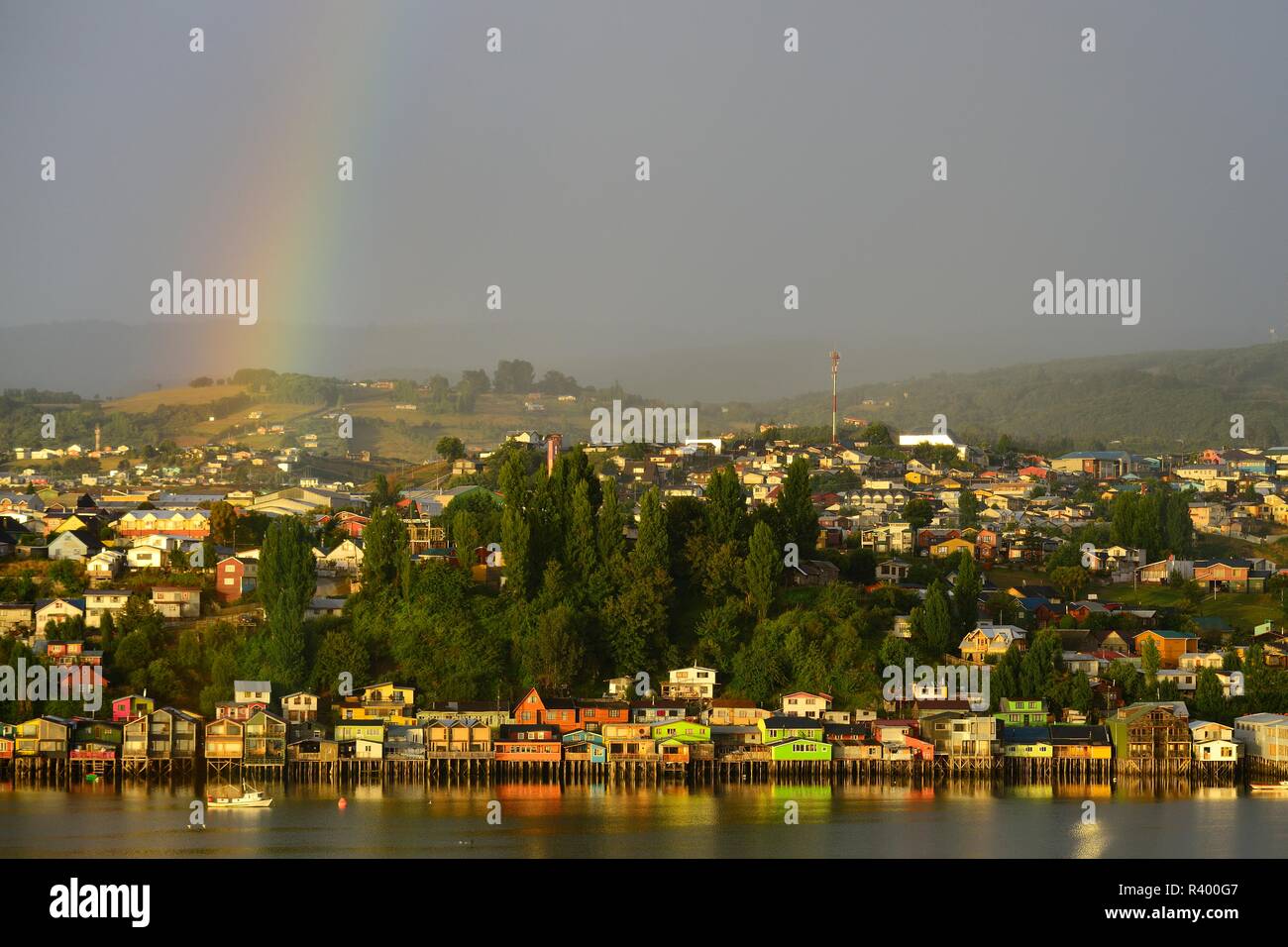 Arc-en-ciel sur la ville avec des maisons sur pilotis, appelées palafitos, dans la lumière du matin, l'île de Castro, Chiloé, Chili Banque D'Images