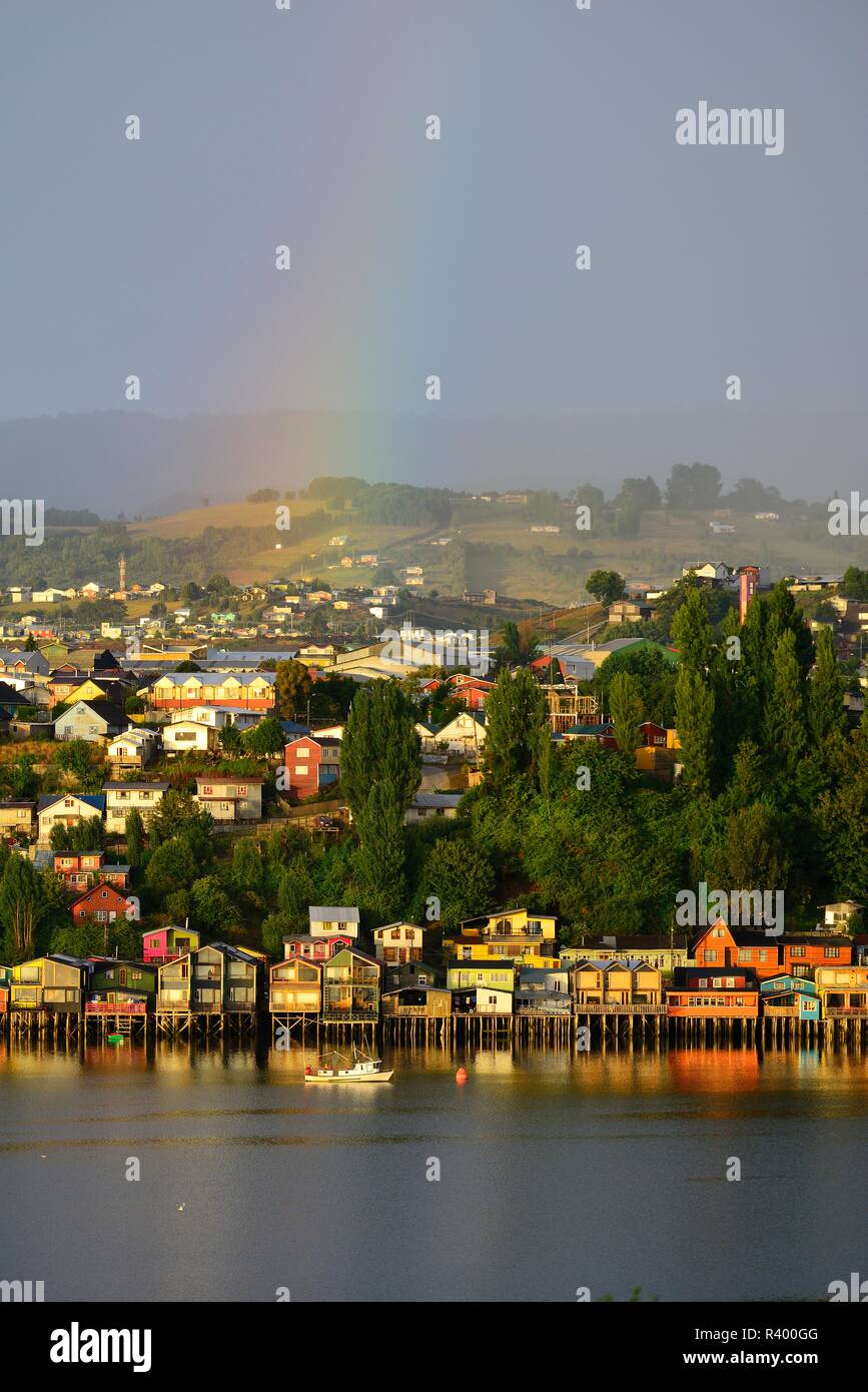 Arc-en-ciel sur la ville avec des maisons sur pilotis, appelées palafitos, dans la lumière du matin, l'île de Castro, Chiloé, Chili Banque D'Images