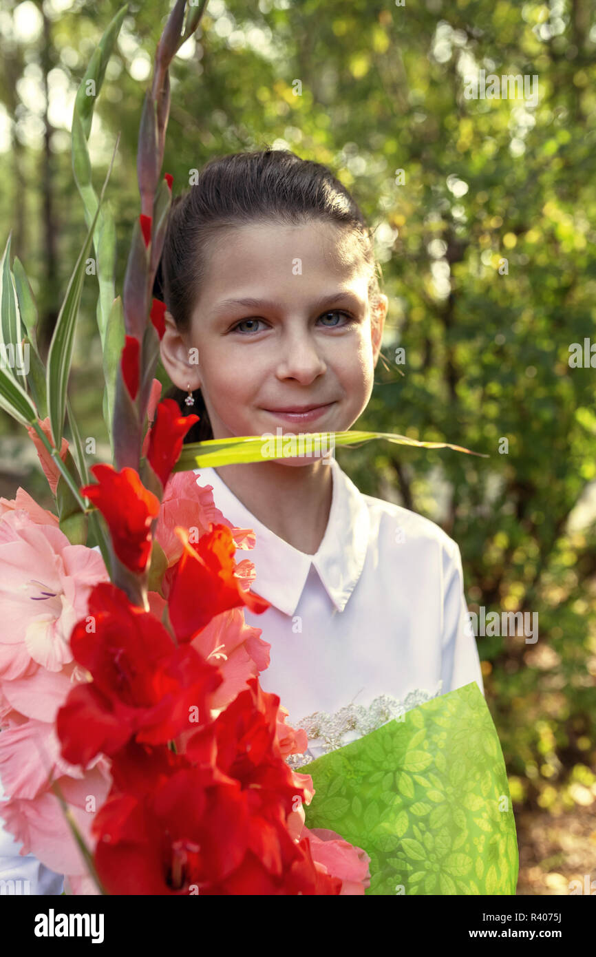 Belle fille avec un bouquet de fleurs de glaïeul sur le premier jour d'école Banque D'Images