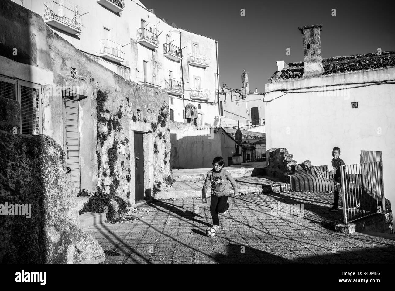 Deux garçons jouent au football dans la rue du Monte Sant'Angelo, Italie, Europe. Banque D'Images