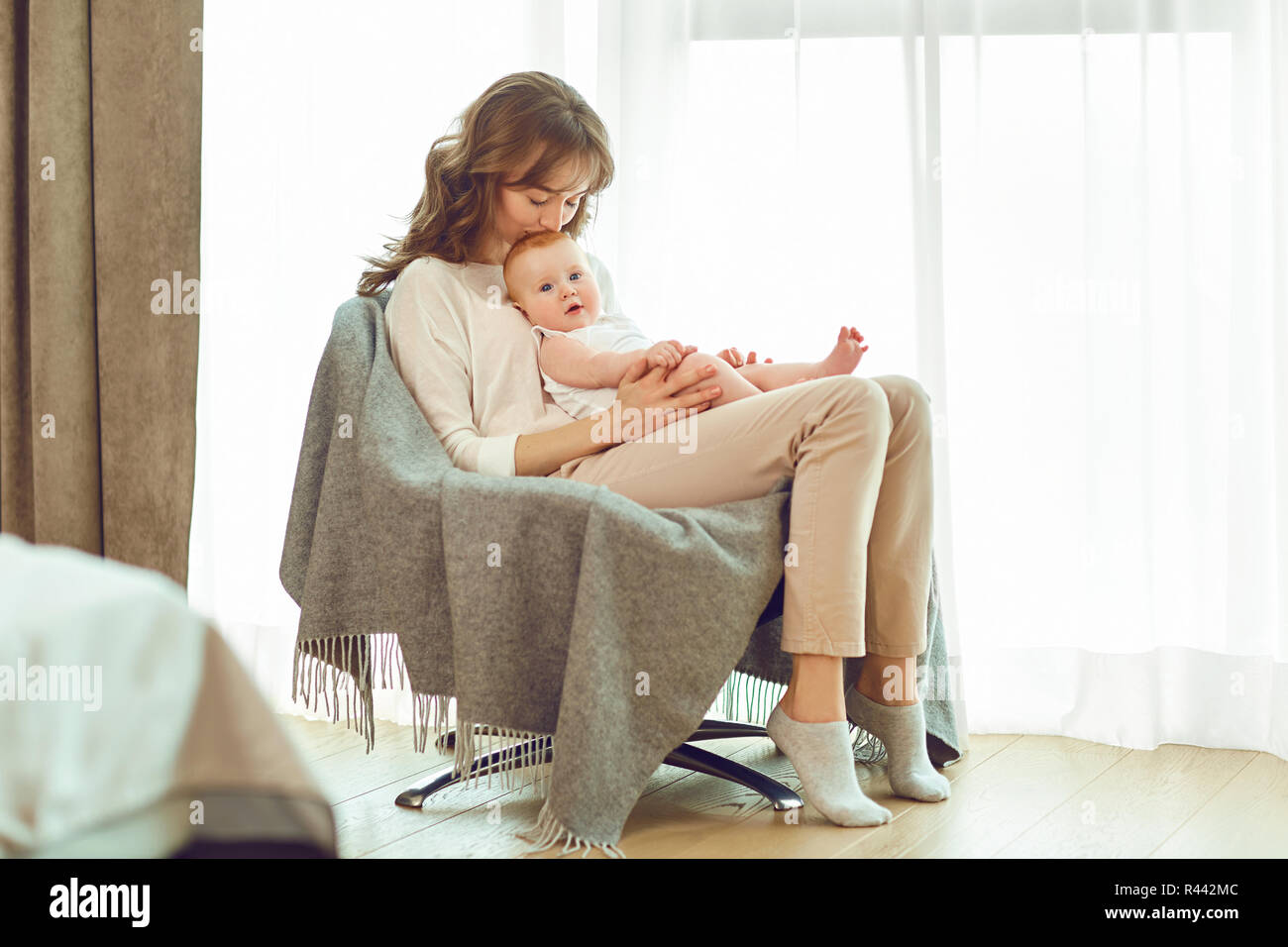 Une mère avec un bébé dans les bras assise sur une chaise. Banque D'Images