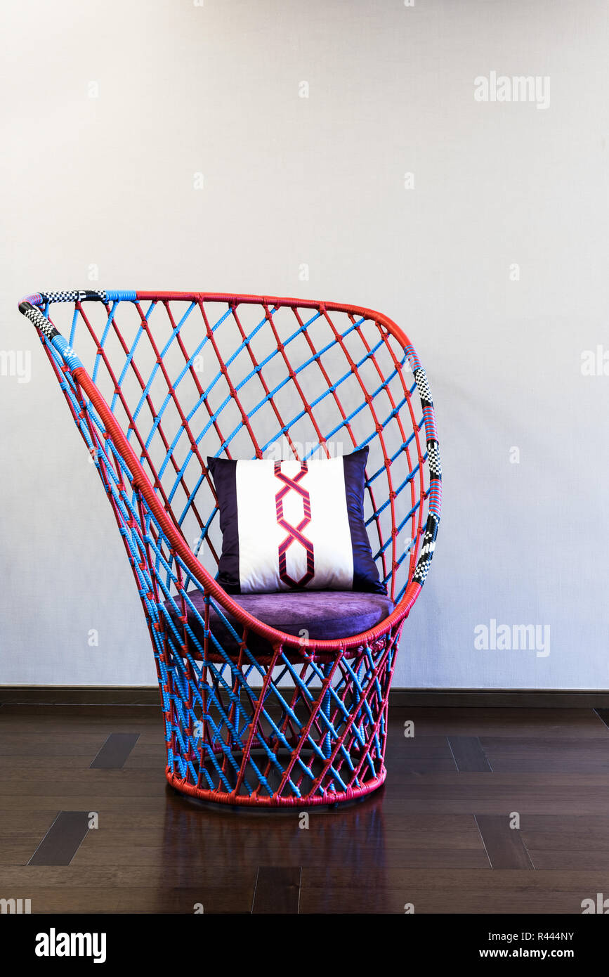 Chaise en osier devant un mur lisse Banque D'Images