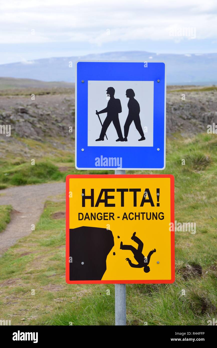 Un panneau en Islande avec deux panneaux pour les randonneurs. L'un est bleu-blanc et montre deux randonneurs, l'un est un noir-rouge-jaune avertissement et montre une personne fal Banque D'Images Un panneau en Islande avec deux panneaux pour les randonneurs. L'un est bleu-blanc et montre deux randonneurs, l'un est un noir-rouge-jaune avertissement et montre une personne fal Banque D'Images