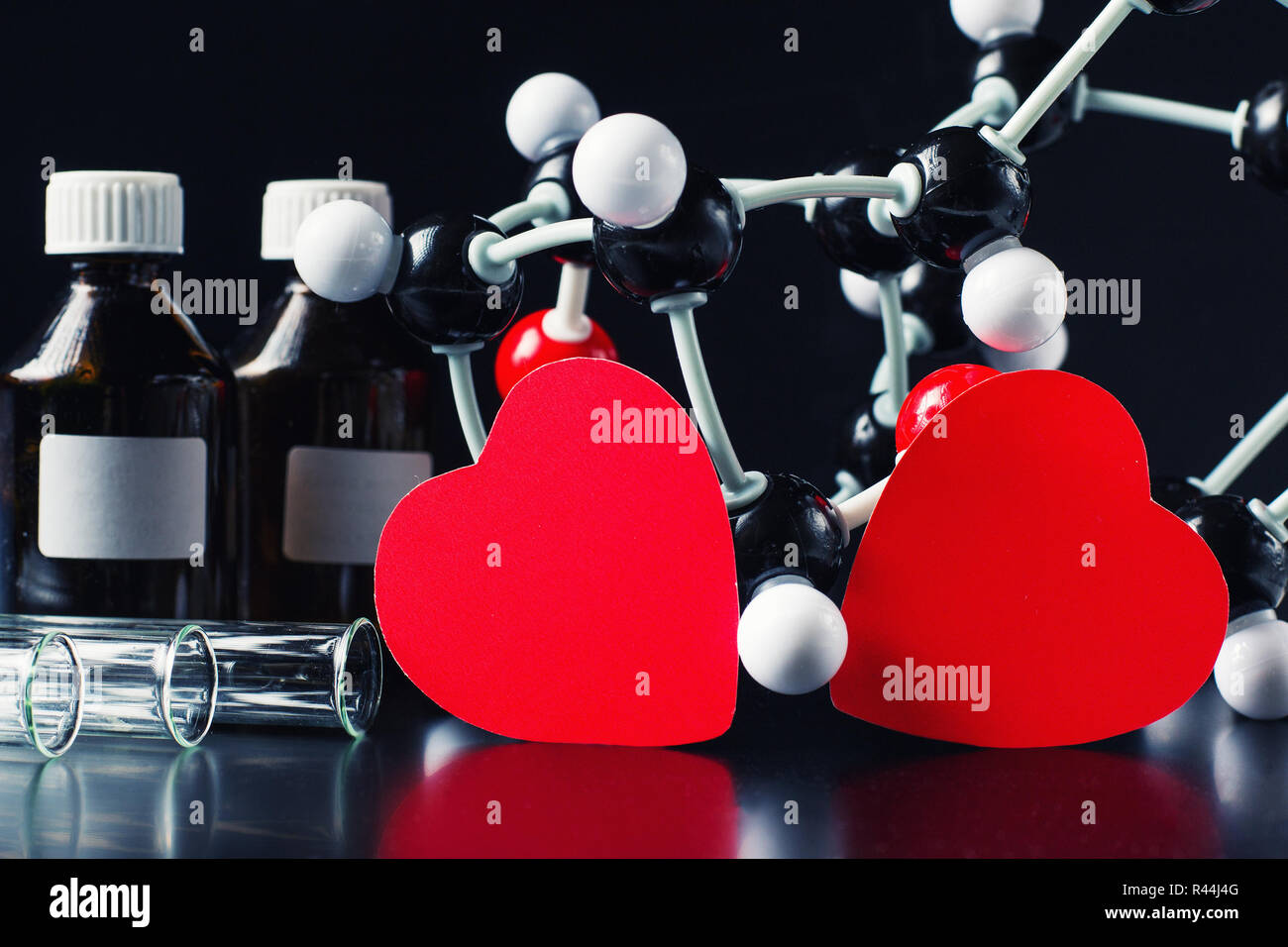 Deux coeurs en papier rouge et la structure moléculaire modèle sur fond noir. Concept de chimie d'amour Banque D'Images