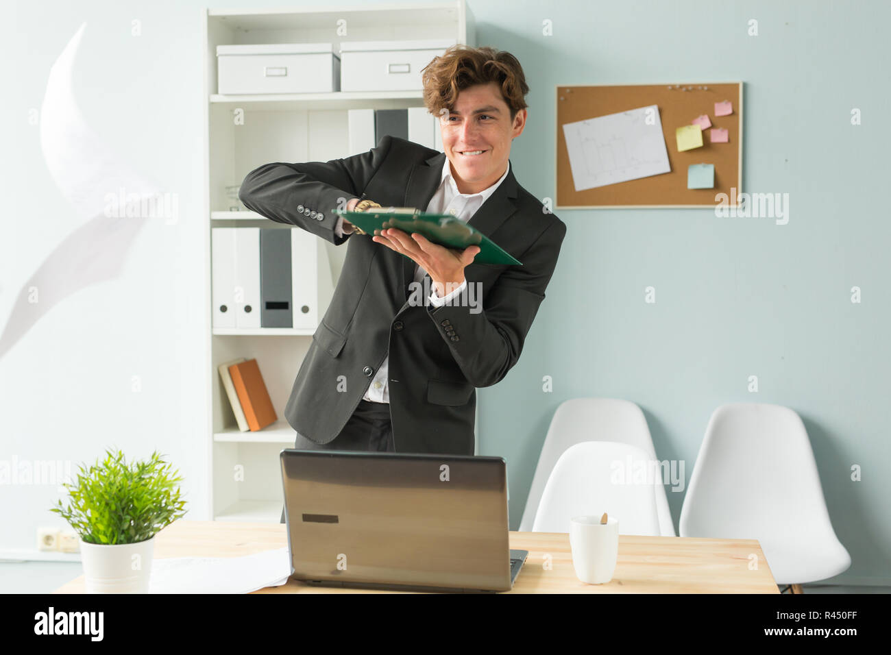 L'humour et les gens d'affaires, concept - beau et jeune homme en litige soulève des feuilles de papier de bureau Banque D'Images