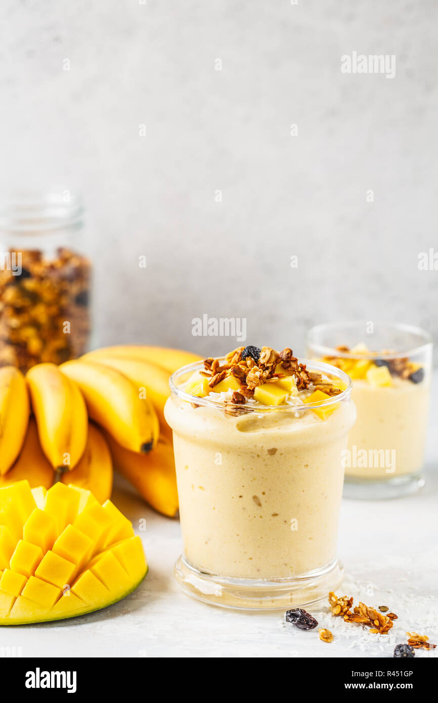 Smoothie banane mangue avec granola et noix de coco dans un pot. Concept alimentaire à base de plantes. Banque D'Images