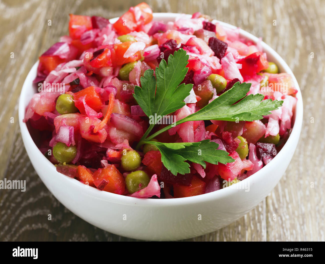 Libre. Salade de betteraves fraîches maison vinaigrette dans un bol blanc sur fond de bois. La cuisine russe traditionnelle.La nourriture végétarienne. Banque D'Images