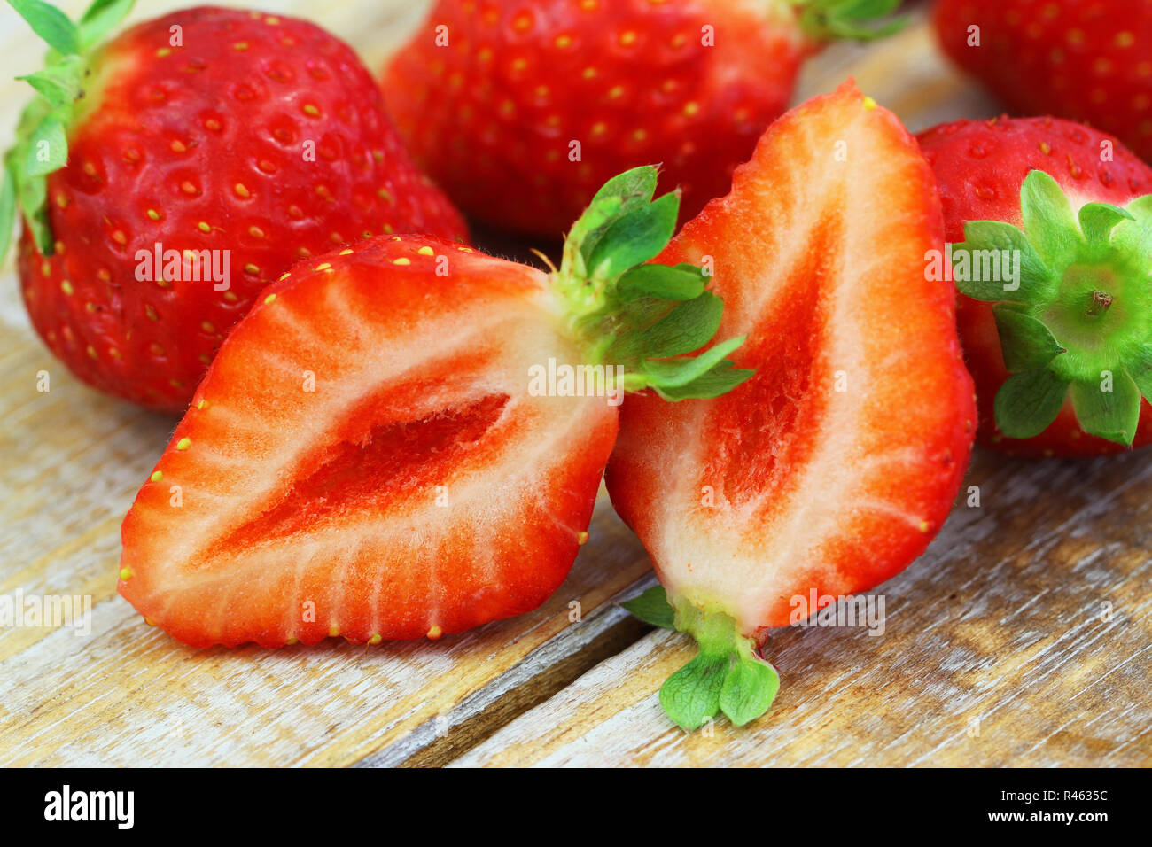 Close up de fraises fraîches coupées en deux sur la surface en bois rustique Banque D'Images