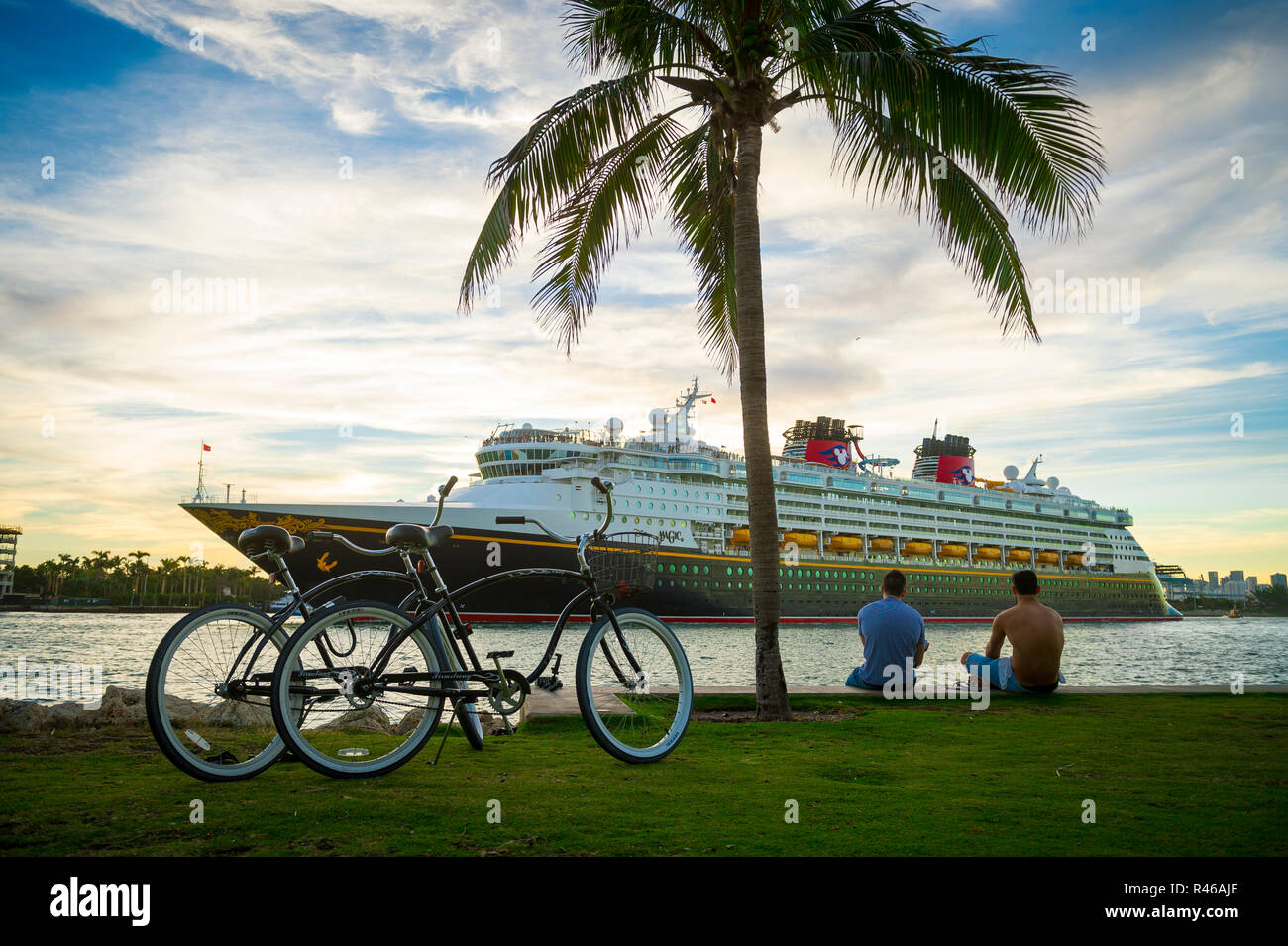 MIAMI - DÉCEMBRE, 2017 : Les visiteurs s'assoient sur le bord de mer de South Pointe Park regarder un Disney Magic bateau de croisière au départ de port. Banque D'Images