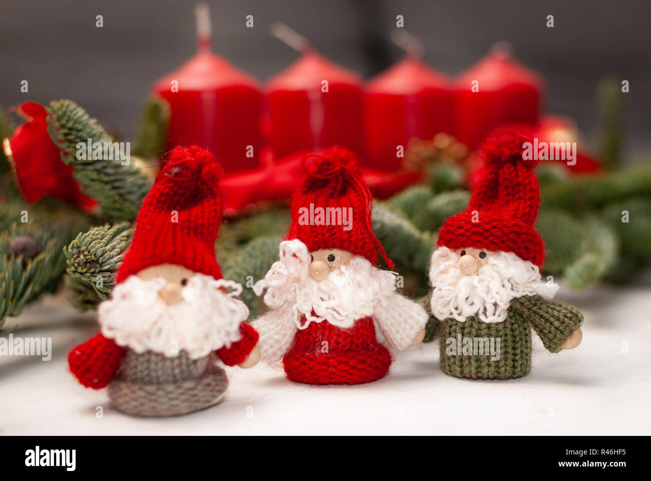 Trois petits nains de Noël en face de quatre bougies et branches de sapin vert Banque D'Images