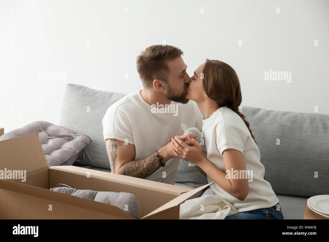Young man and woman kissing sitting on sofa in living room Banque D'Images