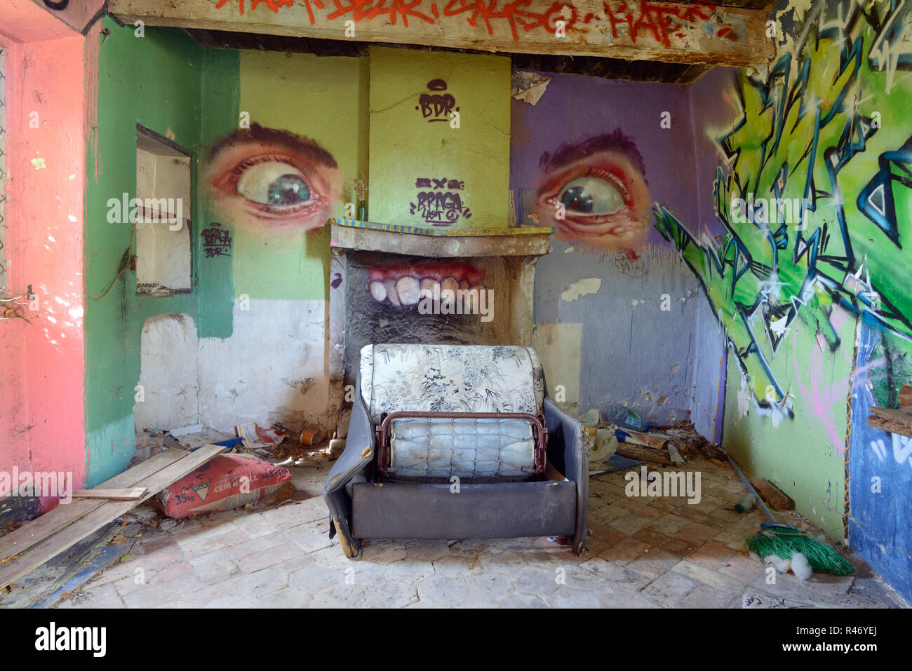 Des murs couverts de graffitis, de détritus éparpillés au sol et canapé cassée dans l'accroupissement Intérieur de maison abandonnée France Banque D'Images
