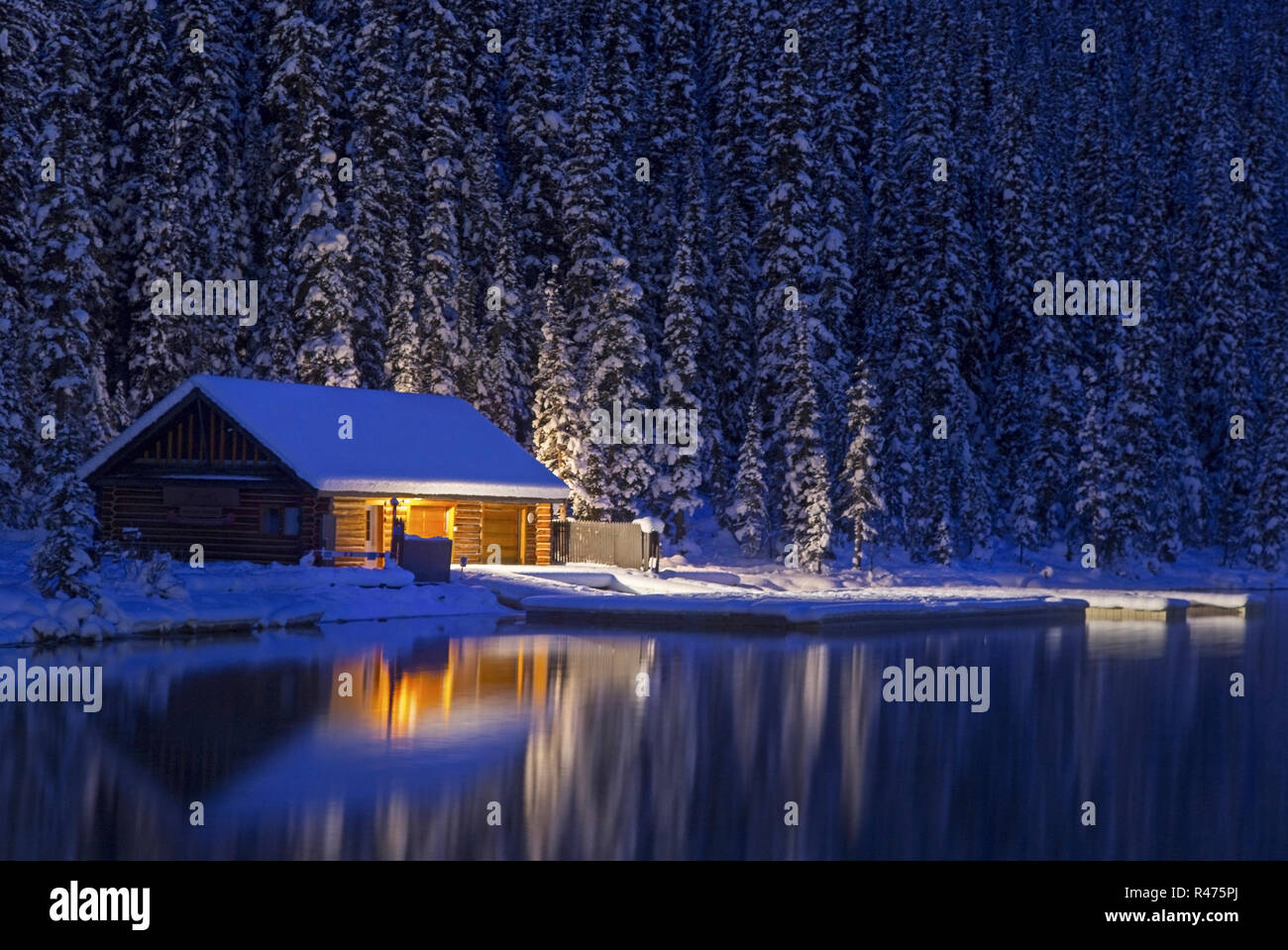 Détail de cabane en bois rustique. Paysage de forêt de neige réflexion de lumière nocturne. Calme Lake Louise eau Parc national Banff hiver Canada montagnes Rocheuses Banque D'Images