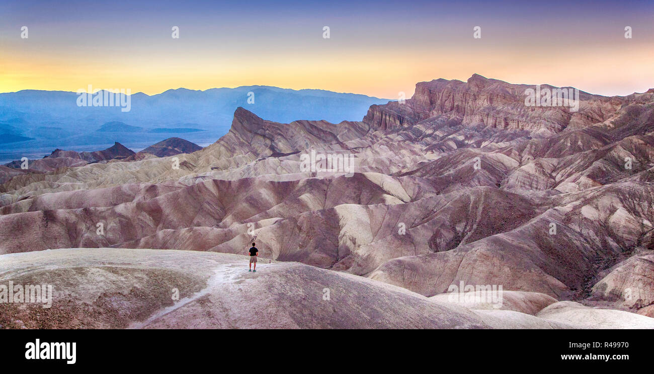 Vue panoramique de l'homme bénéficiant au coucher du soleil célèbre Zabriskie Point dans la belle lumière du soir doré en été, Death Valley National Park, Californie Banque D'Images