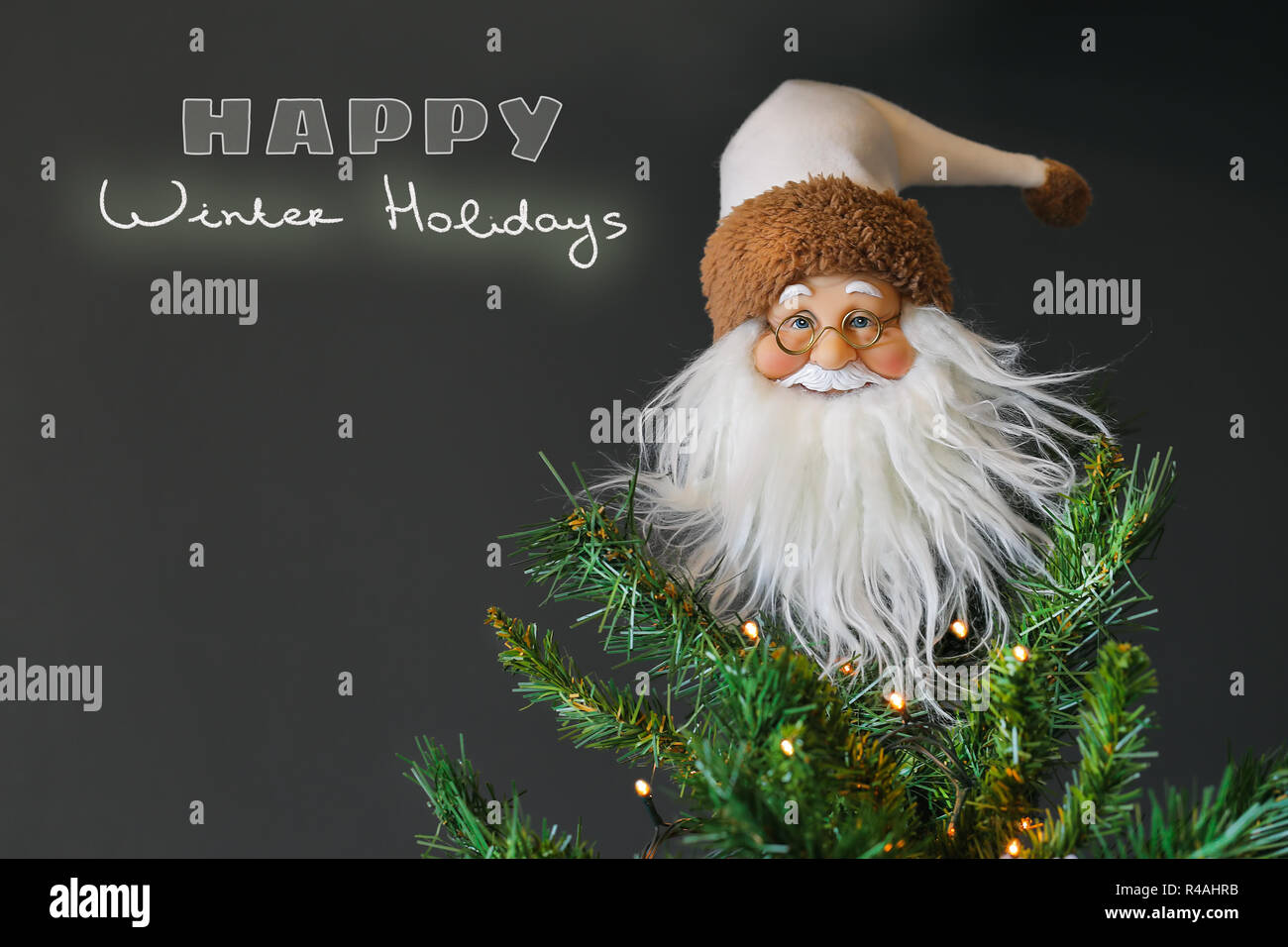 Père Noël jouet comme décor sur l'arbre de Noël sur fond gris, carte de souhaits fête avec du texte, de l'espace heureux vacances d'hiver concept Banque D'Images