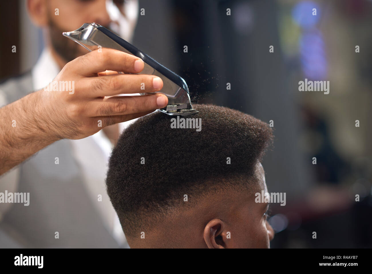 Gros plan du processus de coupe de cheveux dans un salon de coiffure. Maintien de la coiffure qualifiés en mains et corriger 37 forme des cheveux pour clients masculins assis sur une chaise. Concept de coupe de cheveux et le rasage. Banque D'Images