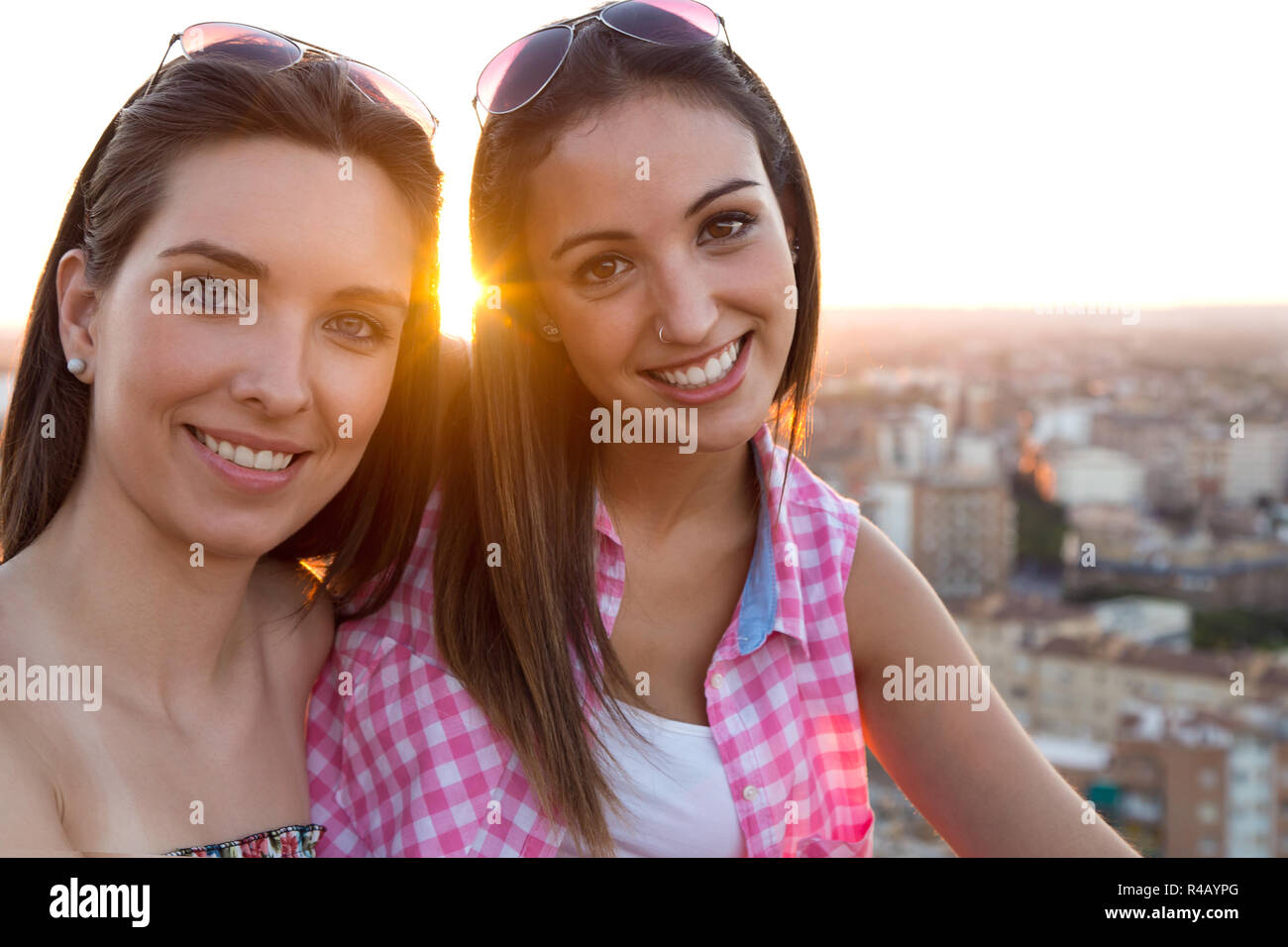 Jolies filles assis sur le toit au coucher du soleil. Banque D'Images