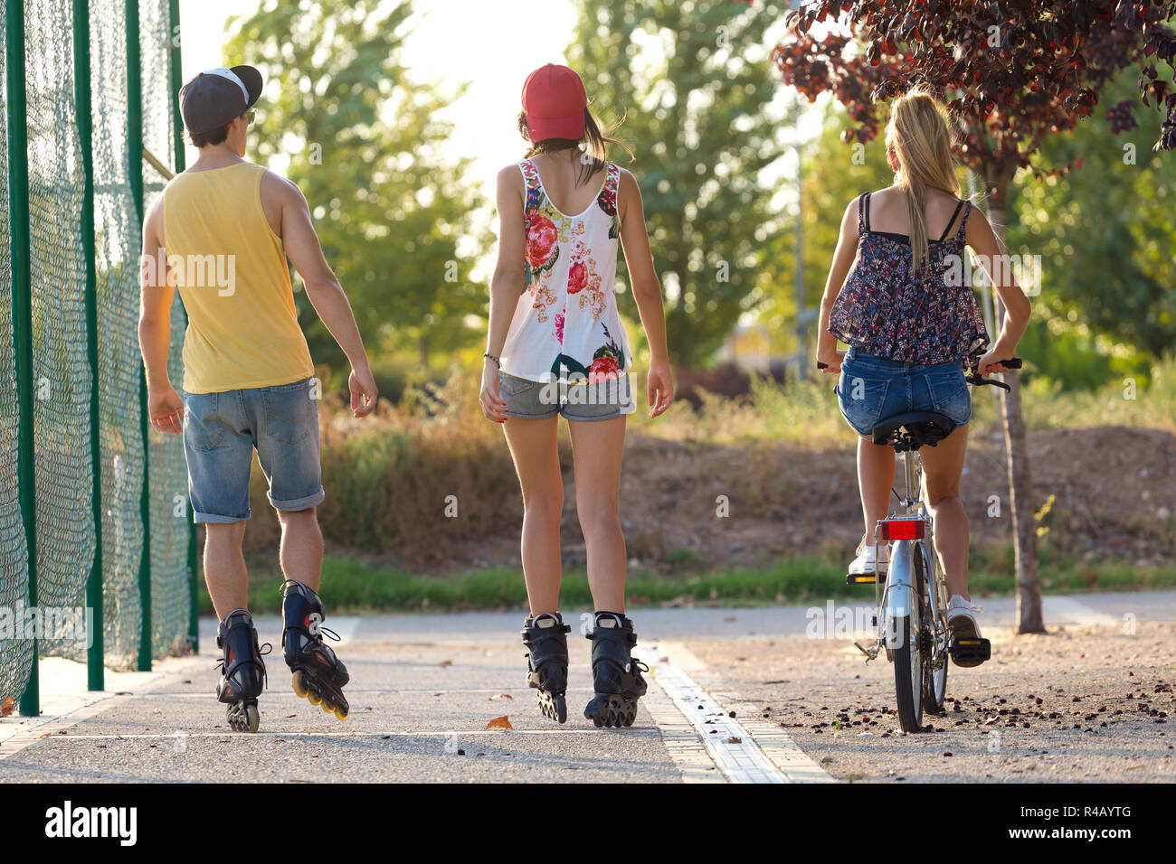 Groupe d'amis avec des patins à roulettes et le vélo dans le parc. Banque D'Images