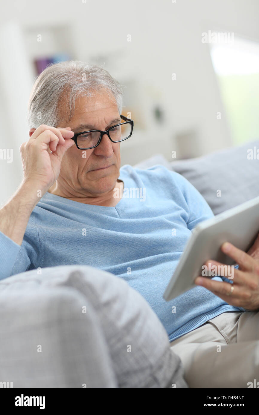Senior man reading news on digital tablet Banque D'Images