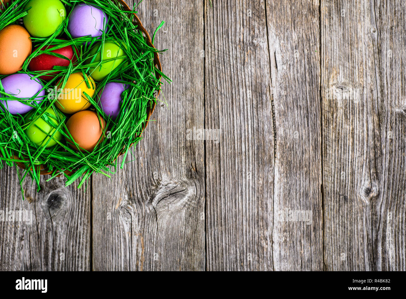 Oeufs de Pâques au printemps, l'arrière-plan avec les oeufs colorés dans leur nid sur table en bois Banque D'Images