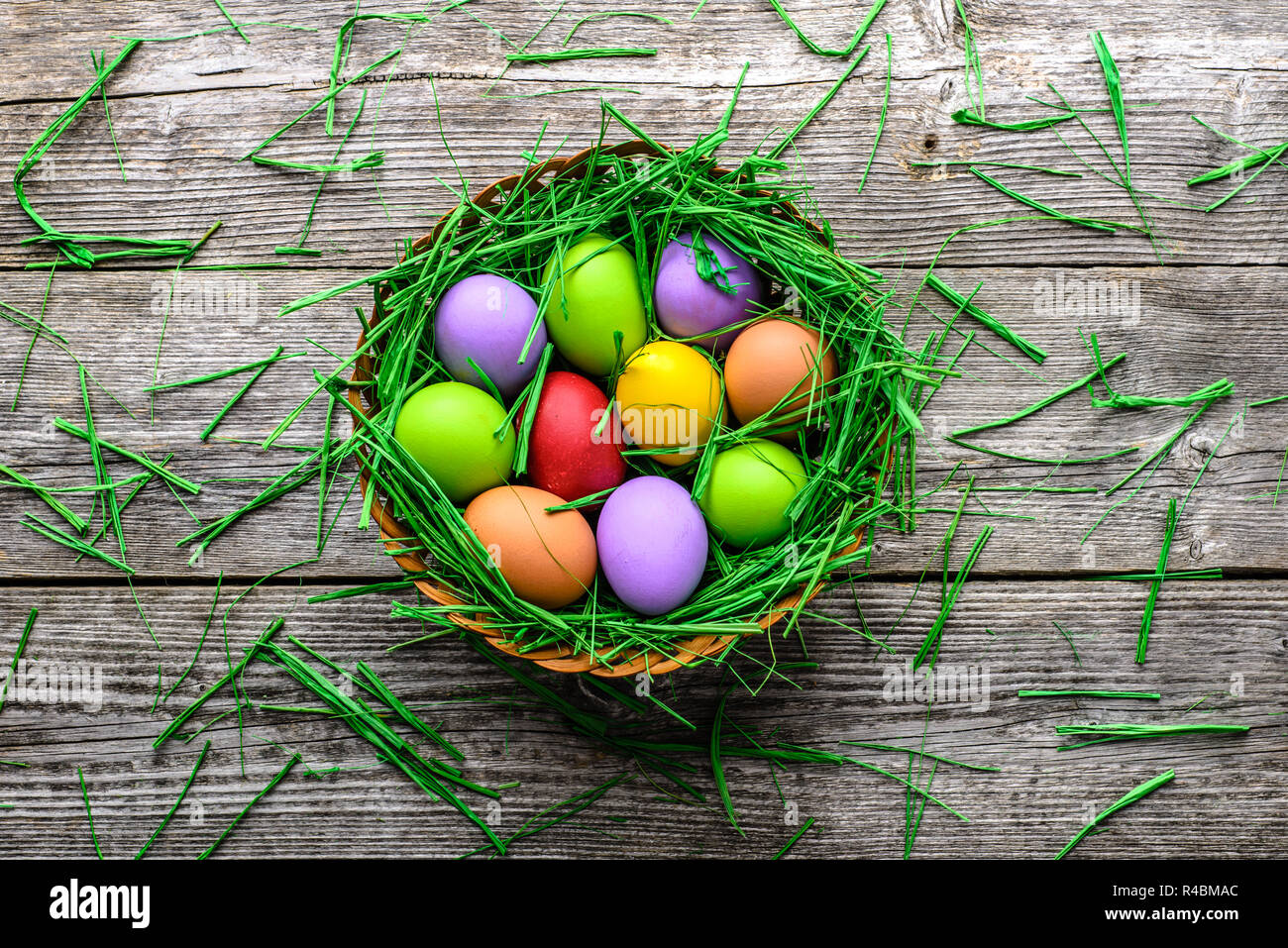 Panier avec des oeufs de Pâques, des œufs colorés sur fond de printemps, sur fond de bois décoration festive Banque D'Images