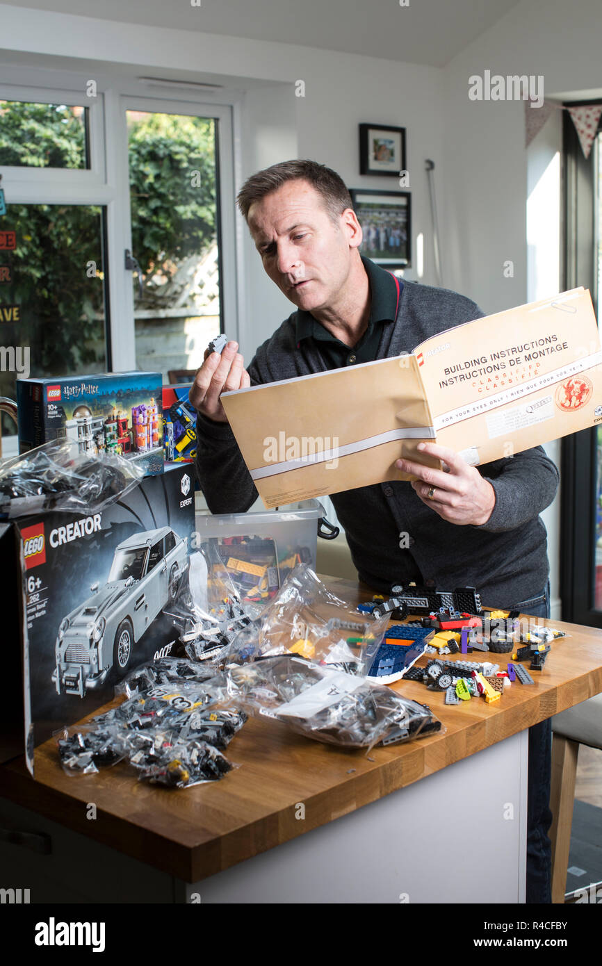 Homme d'âge moyen à la maison lego construction en Angleterre, comme les adultes, sont l'admission à la dépendance à l'édifice en brique de phénomène, Royaume-Uni. Banque D'Images