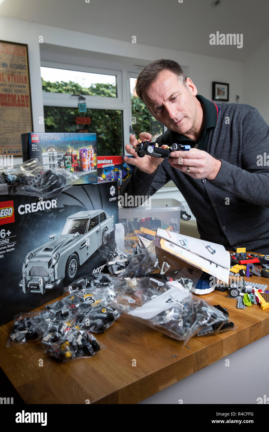 Homme d'âge moyen à la maison lego construction en Angleterre, comme les adultes, sont l'admission à la dépendance à l'édifice en brique de phénomène, Royaume-Uni. Banque D'Images