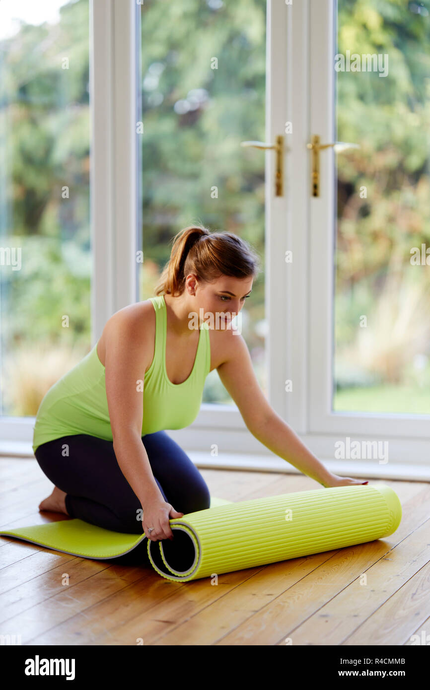 Femme déployant un tapis de yoga Banque D'Images