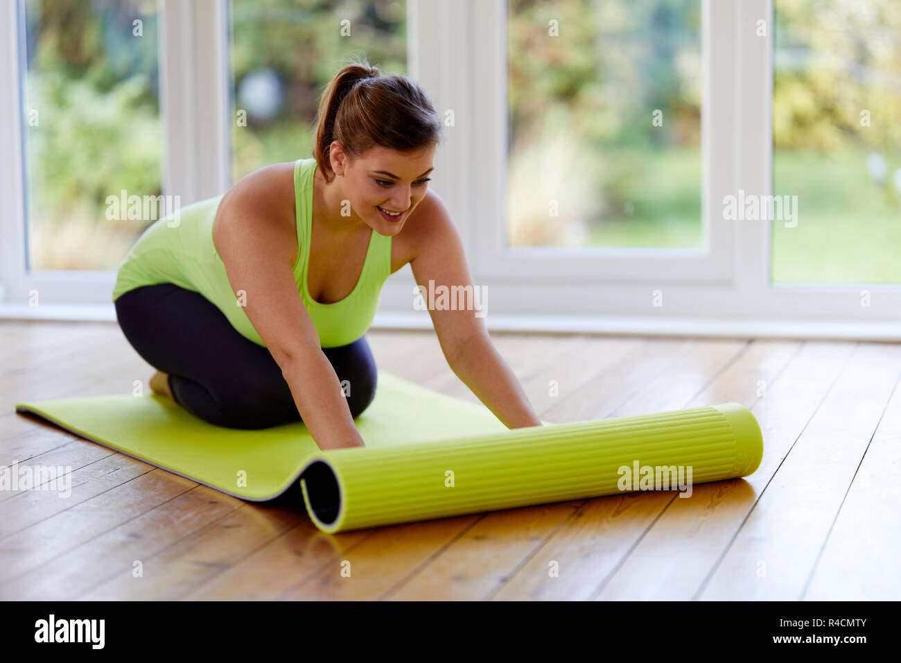 Femme déployant un tapis de yoga Banque D'Images
