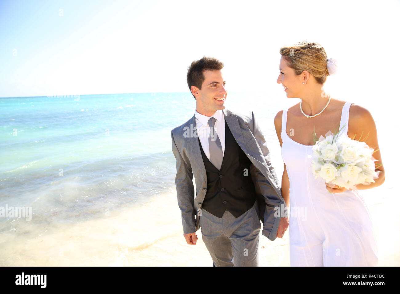 Récemment Mariés couple walking on the beach Banque D'Images