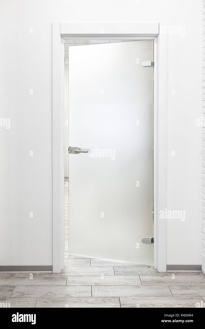 Bureau moderne minimaliste avec intérieur mur blanc et porte en verre dépoli ajar Banque D'Images