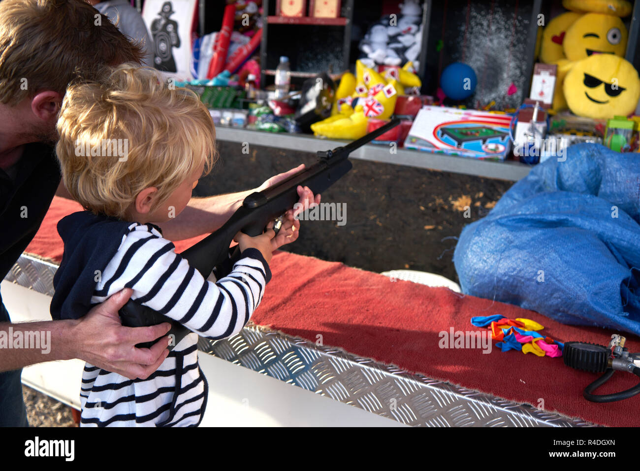 Young Caucasian blonde de 3 à 6 ans tire fusil avec son père à 40 ans à Fun Fair Banque D'Images