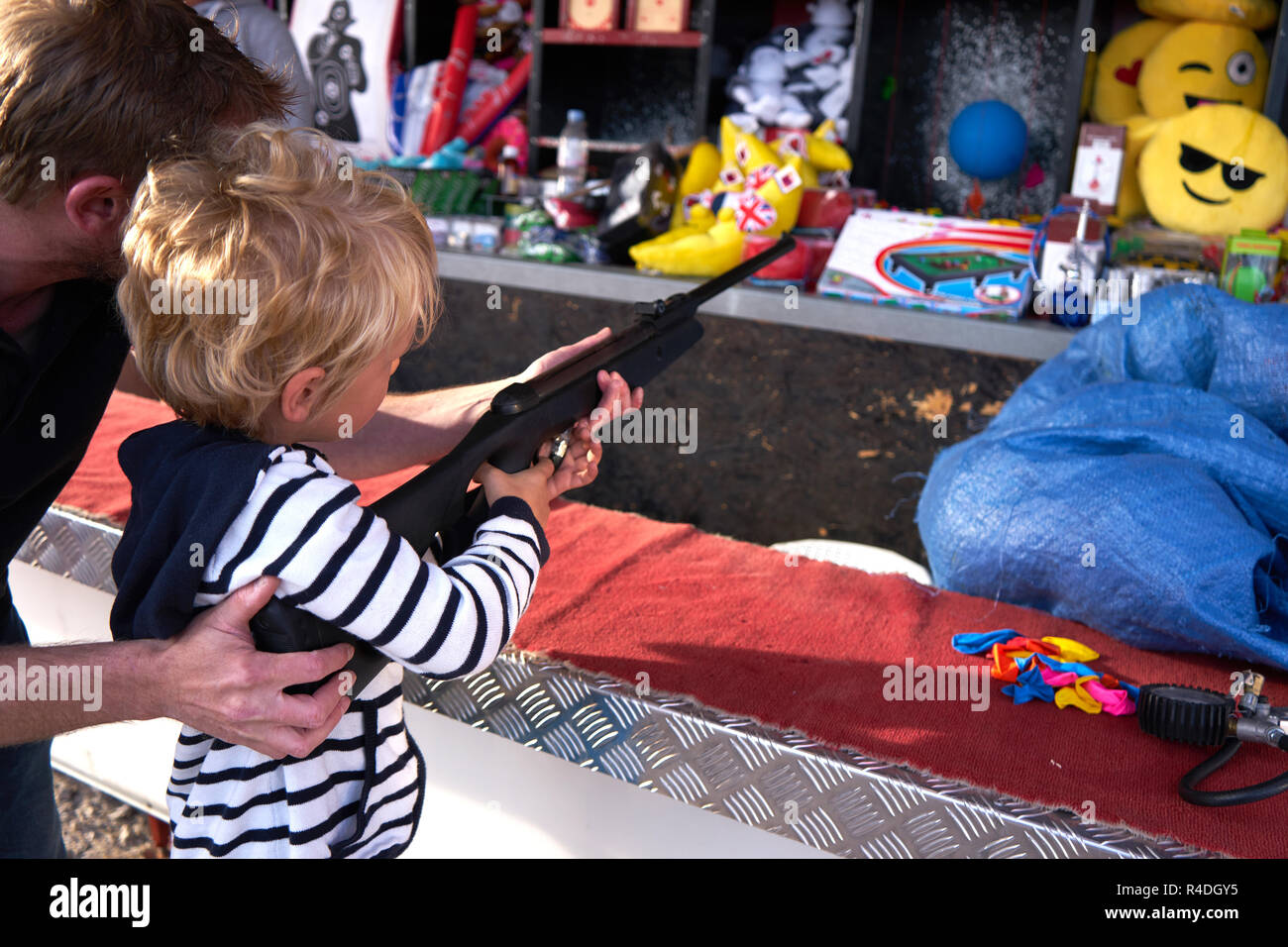 Young Caucasian blonde de 3 à 6 ans tire fusil avec son père à 40 ans à Fun Fair Banque D'Images