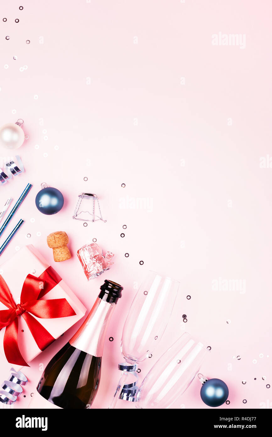 Cadeau de Noël avec arc rouge, bouteille de champagne, deux verres et decorationson bleu fond rose. Belle maison de composition. Arrière-plan vertical avec copie espace. Banque D'Images