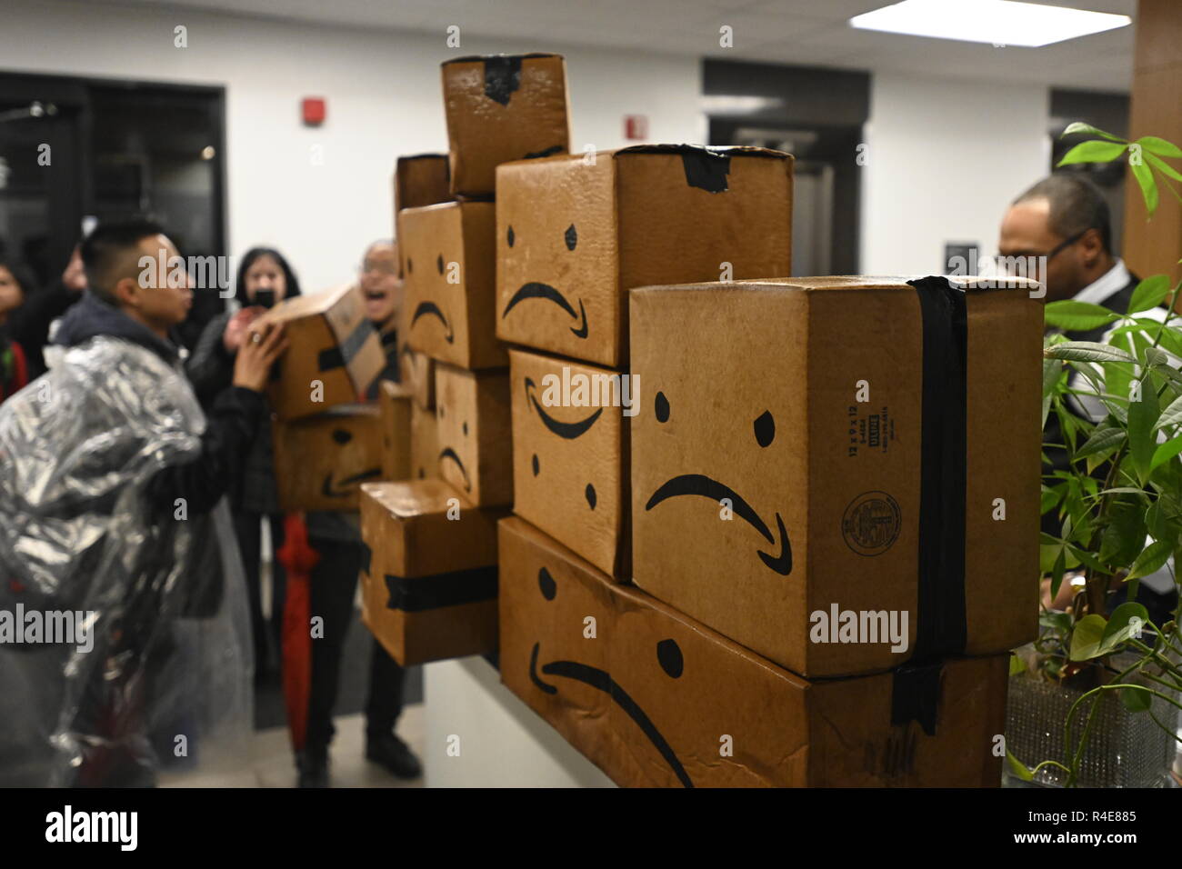 Queens, New York, USA. 26 Nov 2018 des pluies sur une cyber lundi, des manifestants qui protestaient contre le projet de construction d'un nouveau siège à Queens laissez les cases portant une version satirique de Amazon's logo dans le hall de l'immeuble de bureaux de l'Assemblée générale de l'État de New York femme Catherine Nolan, qui soutient le projet. Les objections des manifestants : 2,5 milliards de dollars en subventions de l'État de New York pour le projet et la peur qu'il va nuire à l'industrie existante et augmenter le coût du logement. Crédit : Joseph Reid/Alamy Live News Banque D'Images