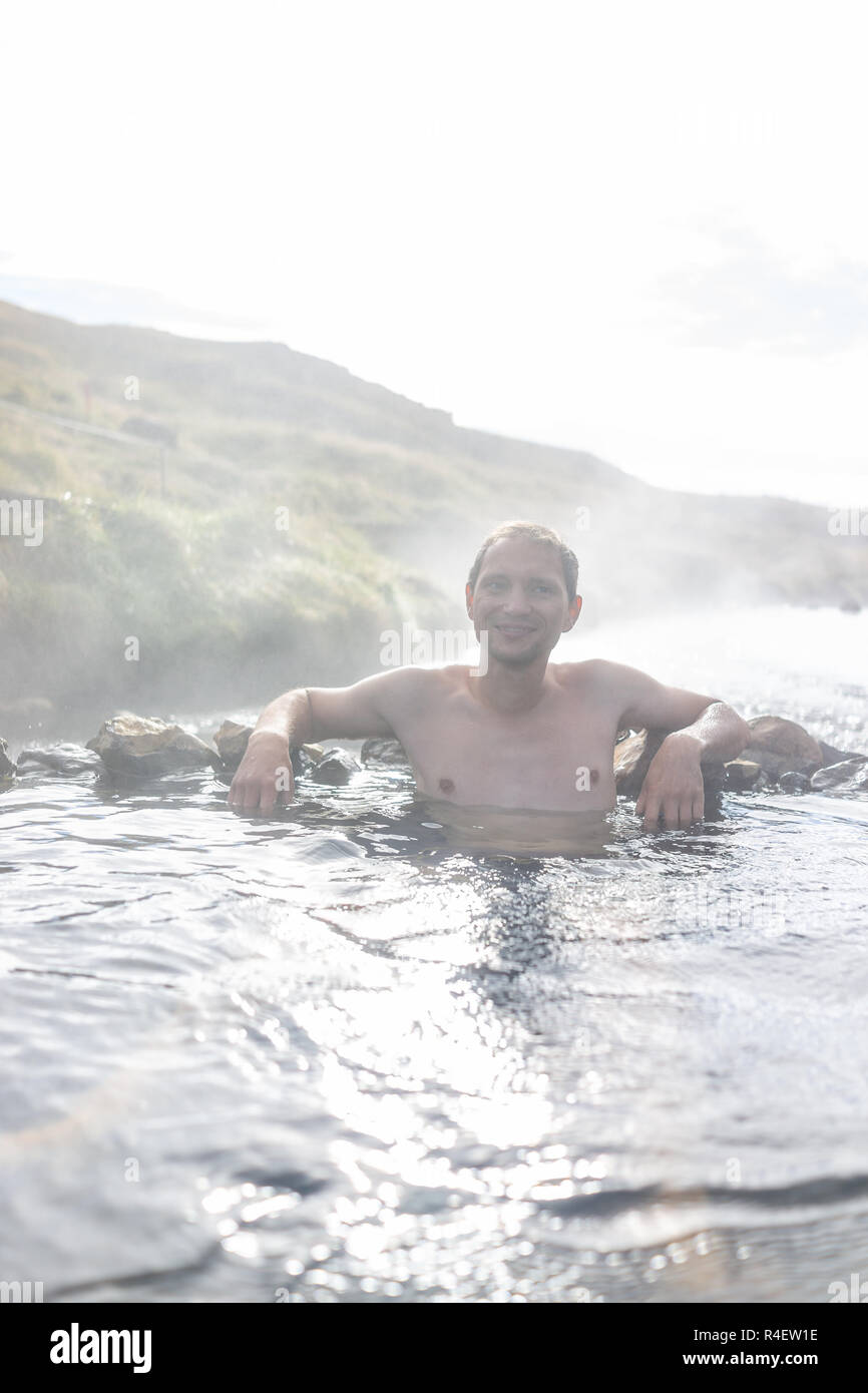 Jeune homme heureux piscine baignade en Hveragerdi Hot Springs sur le sentier en automne, au cours de Reykjadalur matin jour d'été dans le sud de l'Islande, le golden circle, Banque D'Images
