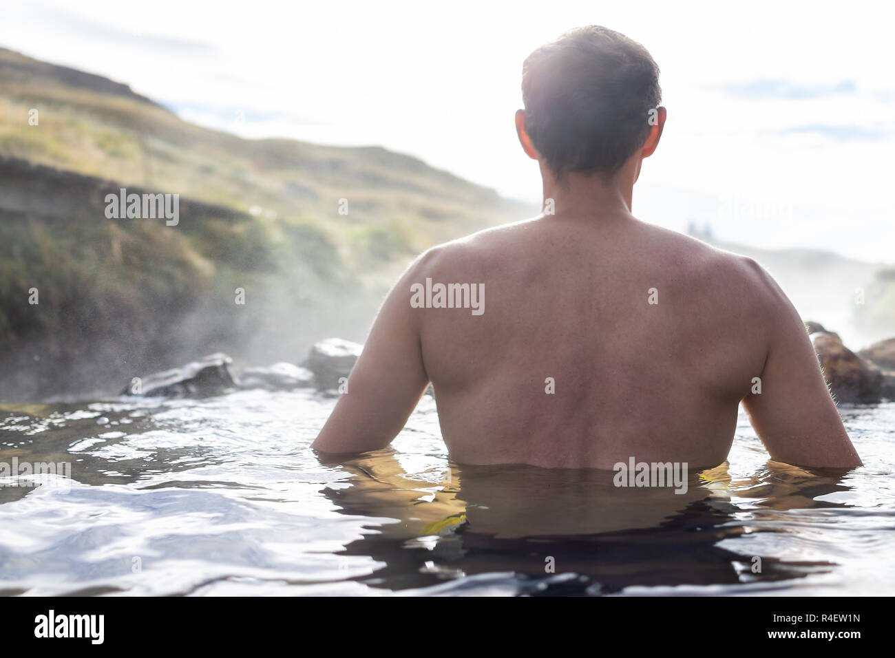 Dos de jeune homme natation baignade dans Hveragerdi Hot Springs, sur piste en matinée, de Reykjadalur jour dans le sud de l'Islande, cercle d'or, roches Banque D'Images