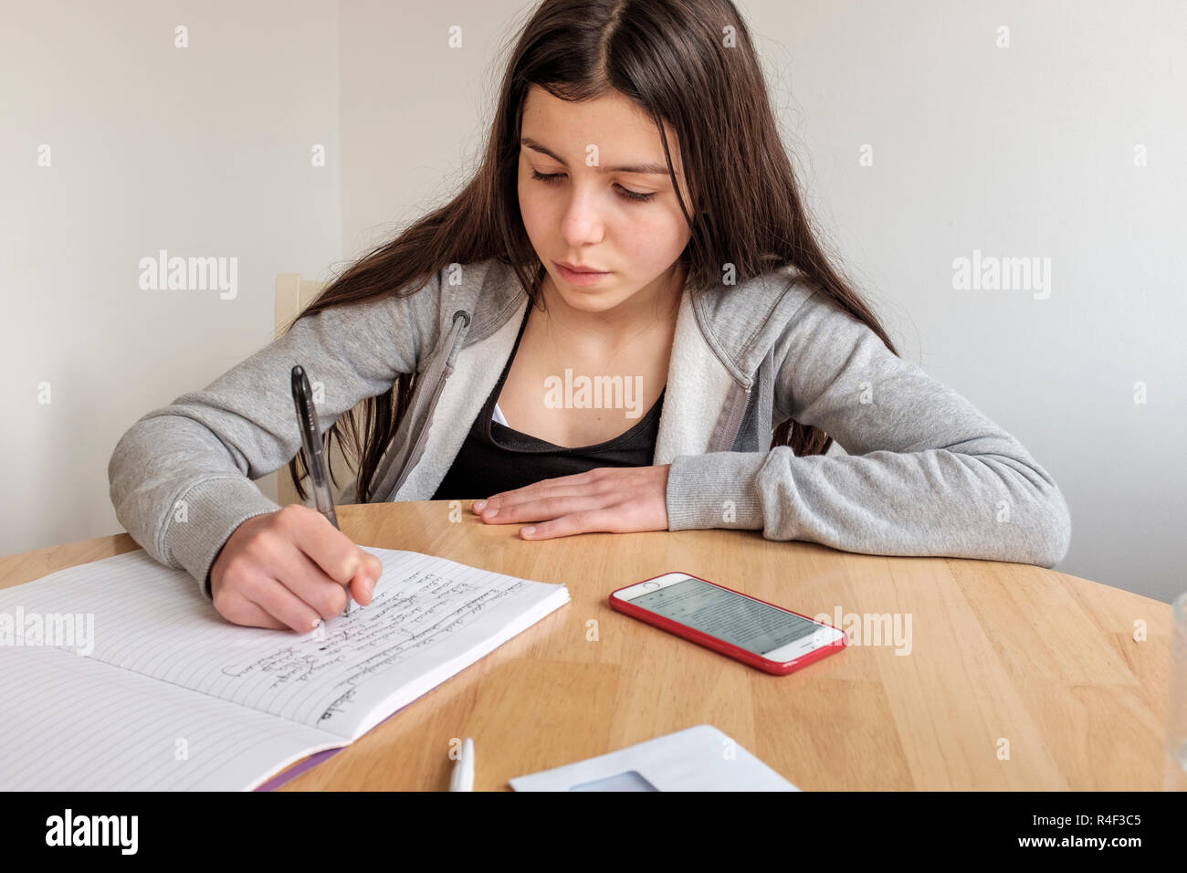 Angleterre, Surrey-Schoolgirl, 13 ans, fait ses devoirs et fait des recherches sur son smartphone Banque D'Images