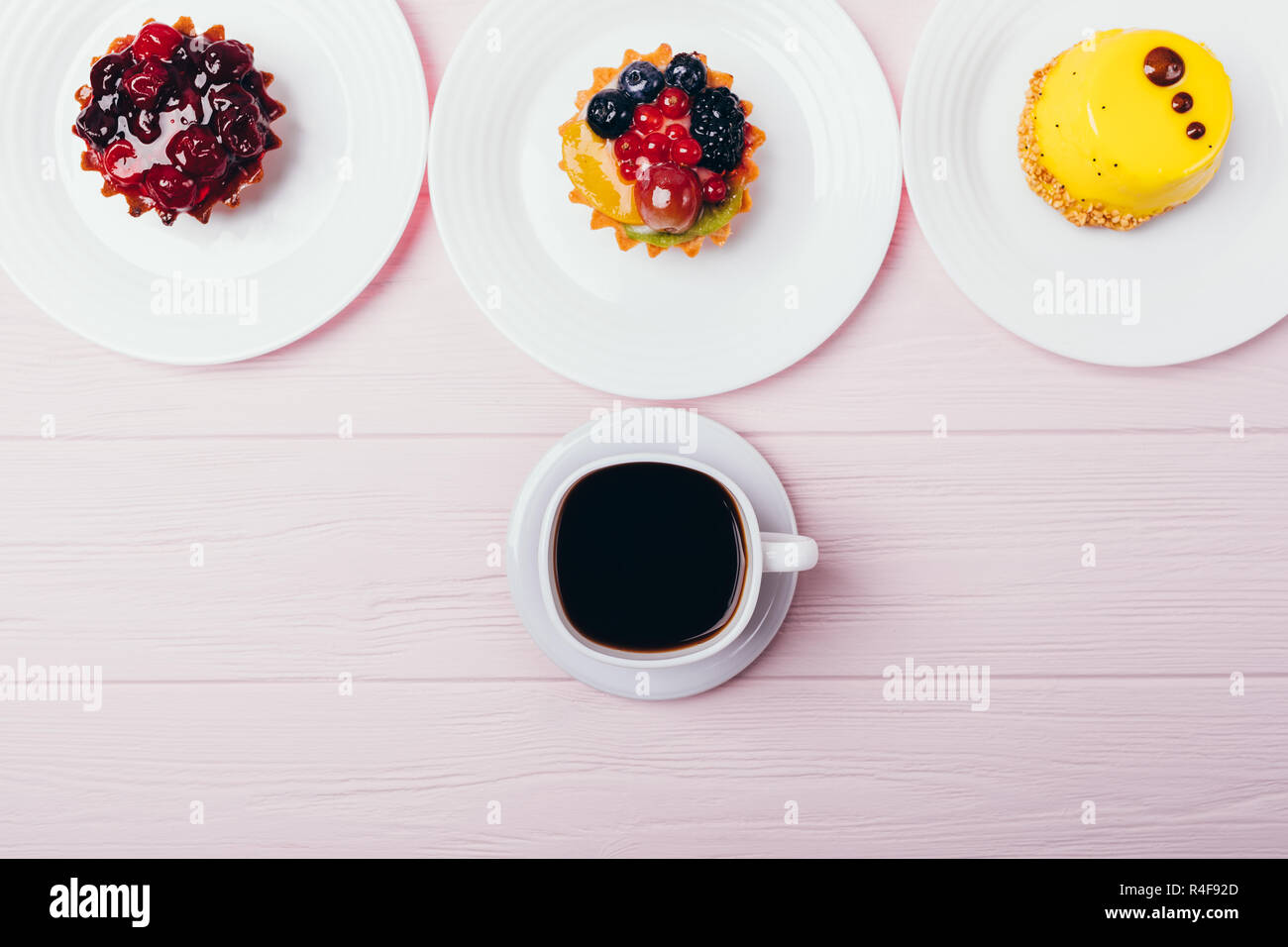 Mise à plat de la composition de délicieux petits gâteaux avec une machine à espresso sur table en bois rose, vue du dessus. Banque D'Images