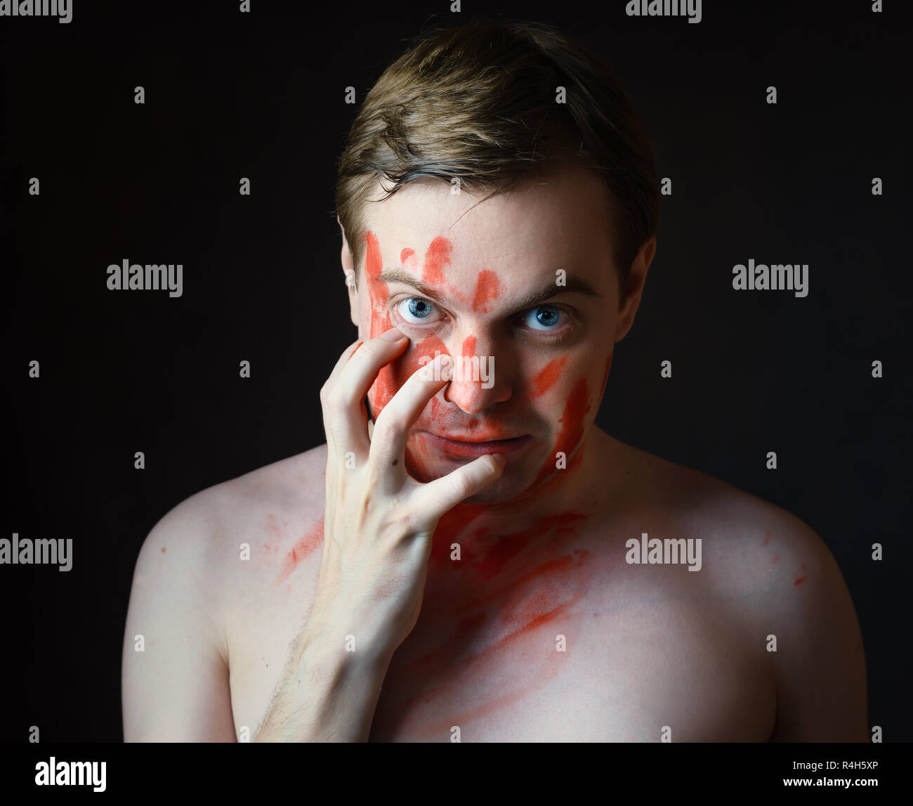 Portrait de jeune homme avec du sang sur son visage et palm sur fond sombre. Banque D'Images