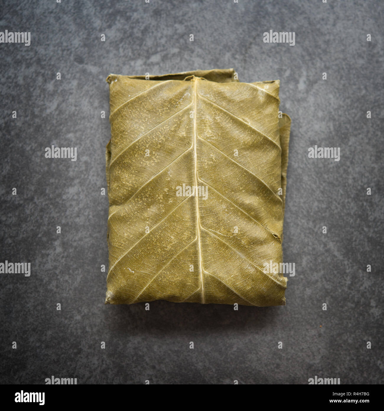 Matières premières le tempeh frais enveloppé dans feuille sur fond sombre, la nourriture végétarienne. Vue d'en haut. Banque D'Images