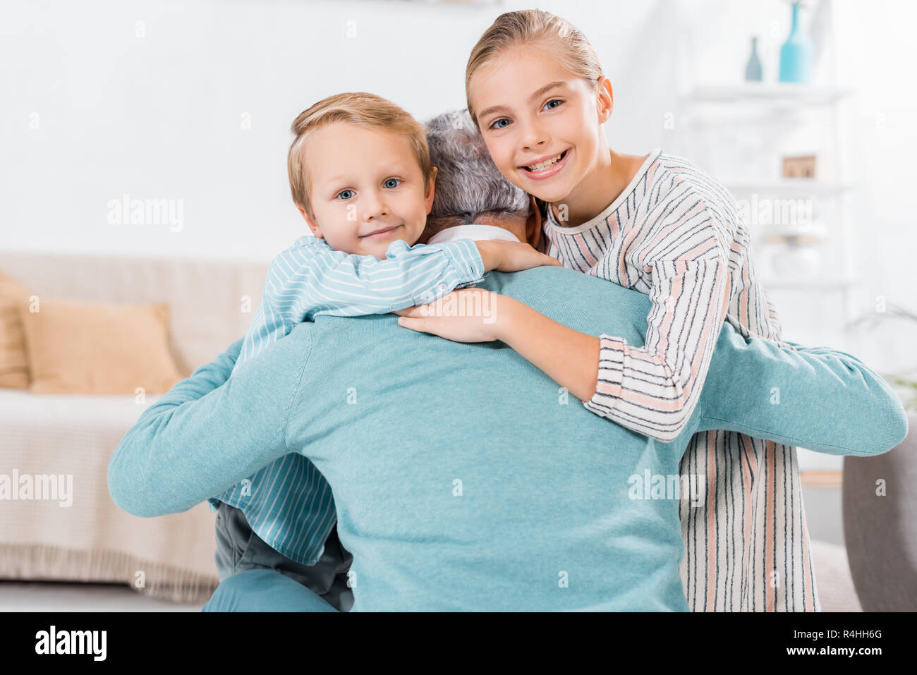 Enfants heureux à la caméra à grand-père à la maison et s'étreindre Banque D'Images