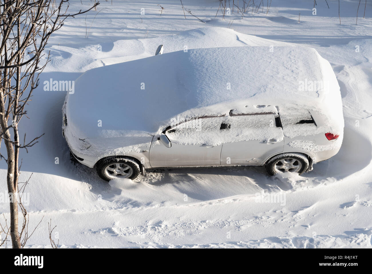Vue de dessus de l automobile blanc stationné dans un banc de neige et couverts de couche de neige après chute de neige. Concept de la conduite en hiver avec de la neige sur la route en arrière Banque D'Images