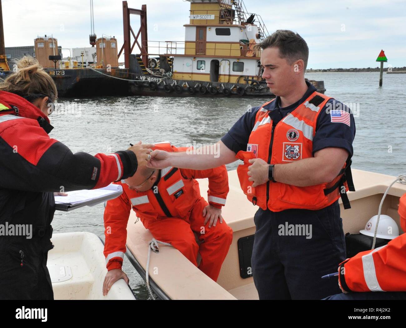 Garde côtière canadienne, le Maître de 3e classe Seth Grayson, un technicien en sciences marines affectés à l'unité de la Sécurité maritime de Portland, Oregon, les mains un stylo pour Paula Gillikin, un gestionnaire de ressources naturelles avec le North Carolina Department of Environmental Quality, de documenter le transfert d'une péniche qui a été déplacée sur le terrain à la réserve de Rachel Carson, une nature préservée, dans une eau peu profonde d'un retrait dans l'avenir, Carteret Comté, N.C., Samedi, Octobre 27, 2018. Le FSE-10 Commandement unifié, composé de la Garde côtière des États-Unis, Caroline du Nord Ressources de la faune et de la Commission, et de Caroline du DEQ, co Banque D'Images