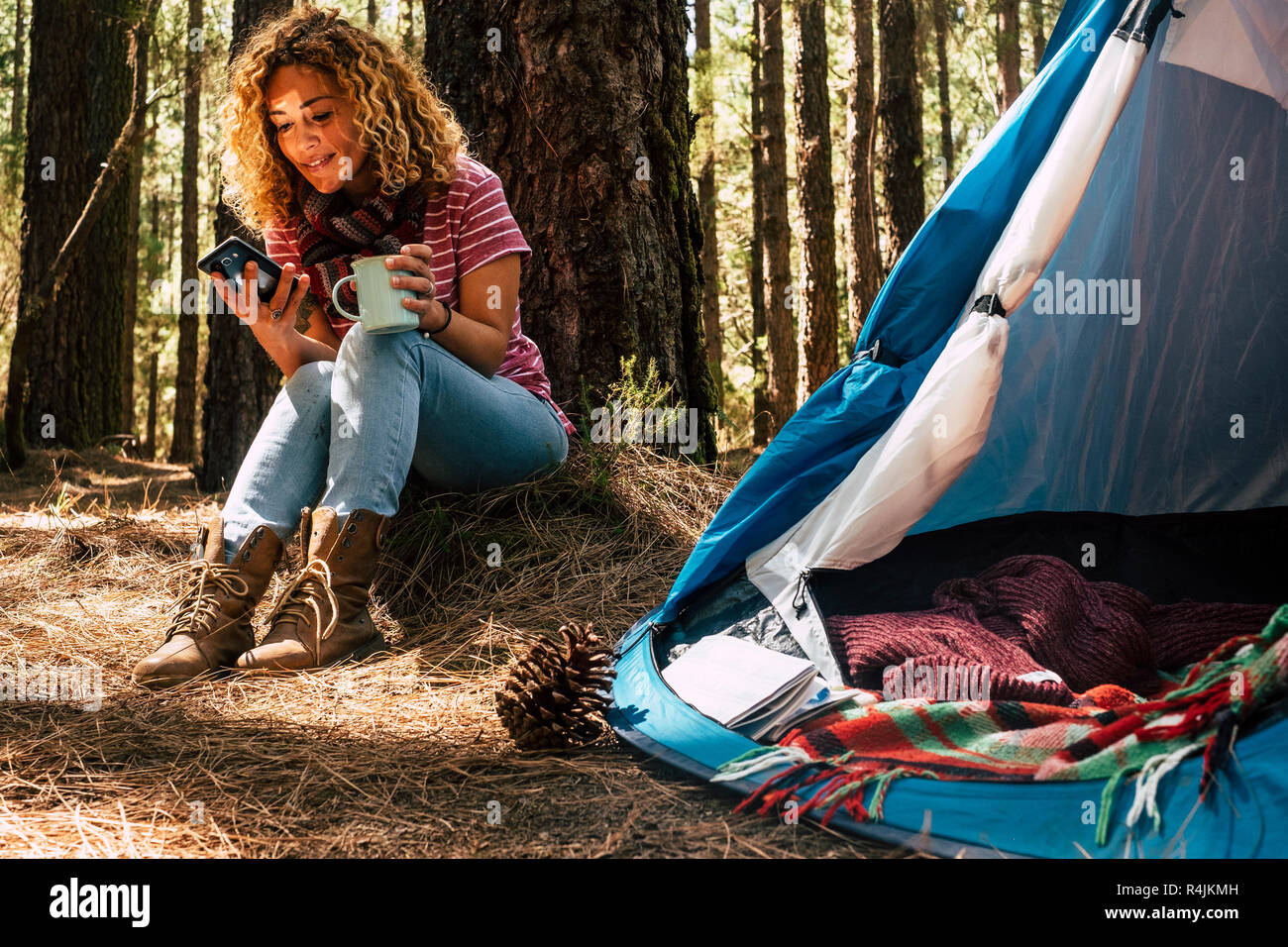 Beau moyen âge portrait femme assise sous un pin dans la forêt a l'aide d'un téléphone mobile avec connexion internet pour voir le site web et Banque D'Images